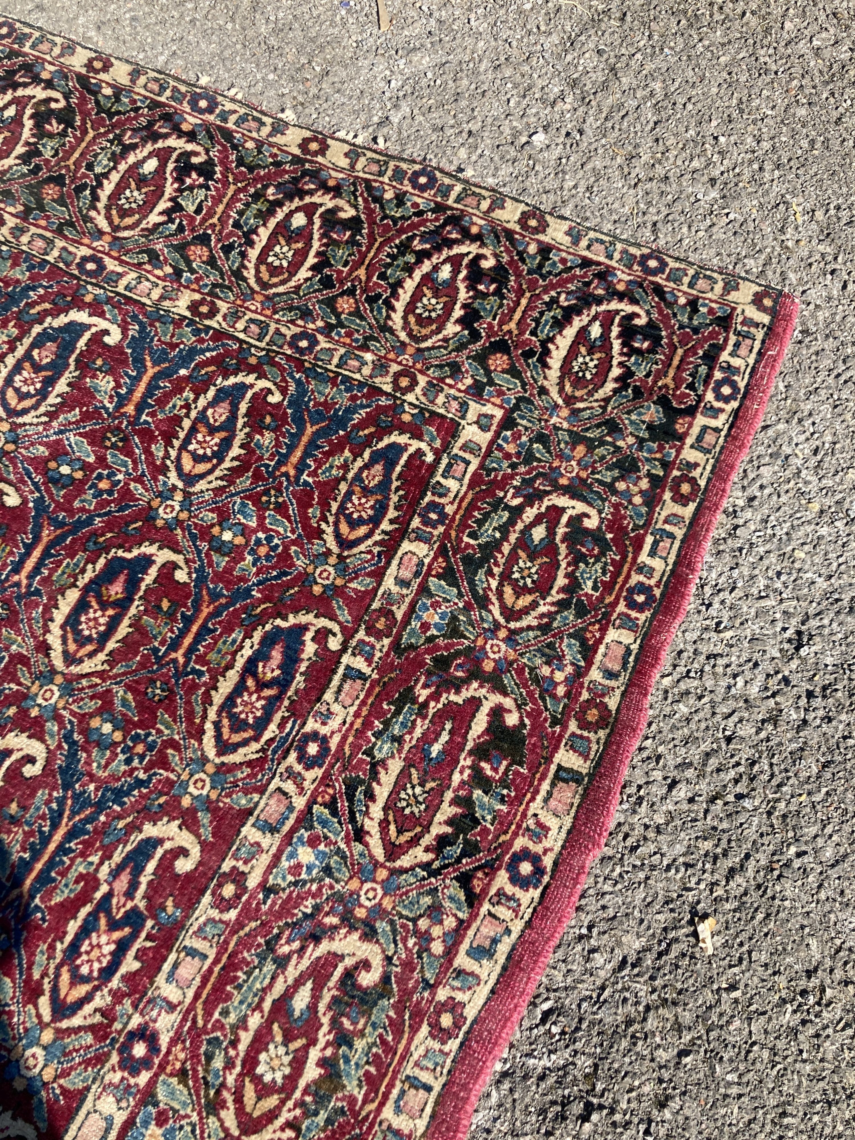 An early 20th century Persian Senneh red ground rug woven with rows of Boteh 218 x 130 cms